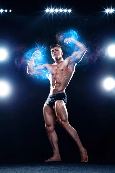 Vahva lihaksikas kehonrakentaja urheilija mies poseeraa ja pumppaa lihaksia mustalla taustalla. Harjoitus kehonrakennus käsite . — kuvapankkivalokuva