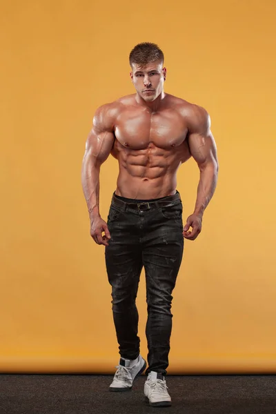 Brutal starke muskulöse Bodybuilder Athlet Mann, der Muskeln auf gelbem Hintergrund aufpumpt. Trainingskonzept Bodybuilding. — Stockfoto