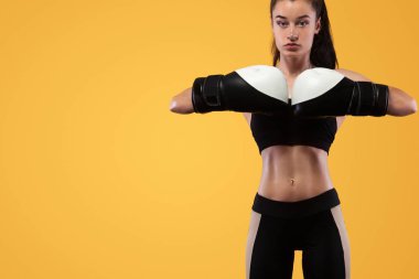 Sporcu, eldiven giymiş kadın boksörü. sarı arka planda. Boks ve fitness konsepti.