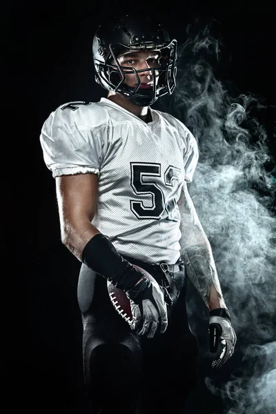 Hráč amerického fotbalového sportovce v helmě na černém pozadí s kouřem. Tapeta sportu a motivace. — Stock fotografie