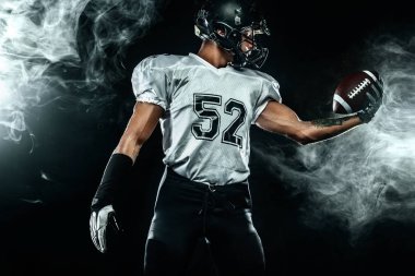 Duman ile siyah arka plan üzerinde kask Amerikan futbol sporcusu oyuncu. Spor ve motivasyon duvar kağıdı.