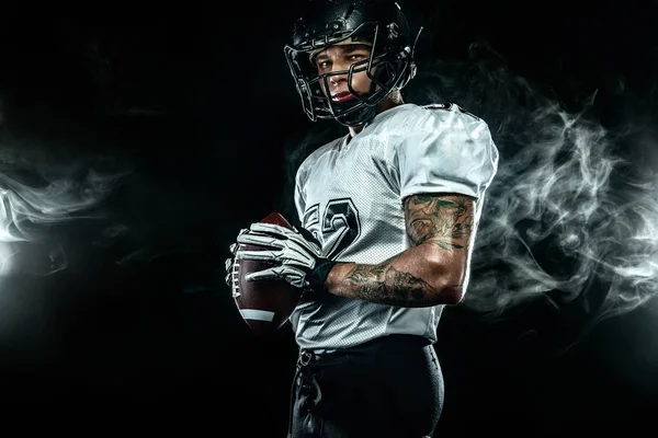 Joueur sportif américain de football en casque sur fond noir avec de la fumée. Sport et papier peint de motivation . — Photo