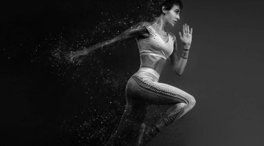 Fitness ve spor motivasyonu... Güçlü ve fit atletik, kadın sprinter veya koşucu, spor giyim giyen yangın kırmızı arka plan üzerinde çalışan.