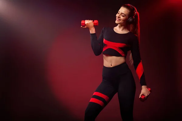 Sportowa kobieta Fit, sportowiec z hantlami sprawia, że ćwiczenia fitness na czerwonym tle. Fitness i motywacja pracęnaszego. — Zdjęcie stockowe
