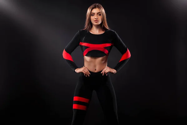 Femme athlétique forte, posant sur fond noir portant des vêtements de sport. Fitness et motivation sportive. Espace de copie . — Photo