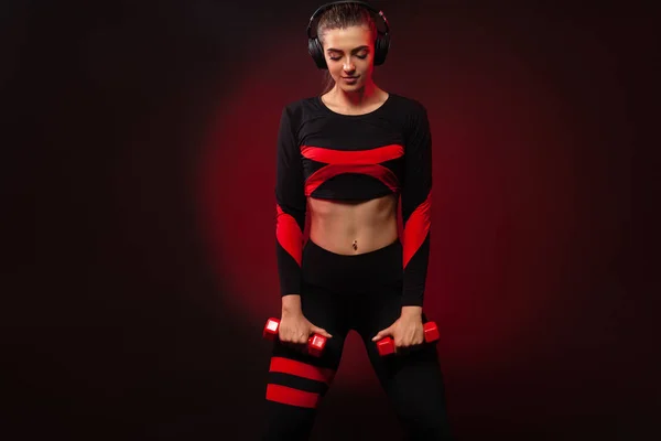 Donna in forma sportiva, atleta con manubri fa esercizio di fitness su sfondo rosso. Fitness e motivazione del lavoro . — Foto Stock