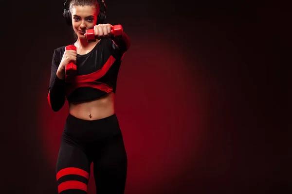 Sportowa kobieta Fit, sportowiec z hantlami sprawia, że ćwiczenia fitness na czerwonym tle. Fitness i motywacja pracęnaszego. — Zdjęcie stockowe