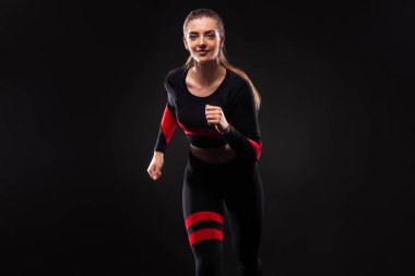Güçlü atletik kadın koşucu, spor giyen siyah arka plan üzerinde çalışan. Fitness ve spor motivasyonu. Kopyalama alanı ile Sprinter kavramı.