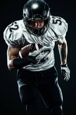 Kask lı Amerikalı futbolcu siyah arka planda hareket halinde. Spor ve motivasyon duvar kağıdı.