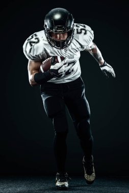 Kask lı Amerikalı futbolcu siyah arka planda hareket halinde. Spor ve motivasyon duvar kağıdı.