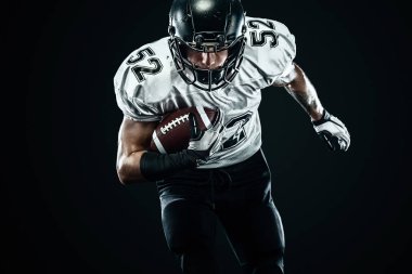 Kask lı Amerikalı futbolcu siyah arka planda hareket halinde. Spor ve motivasyon duvar kağıdı.