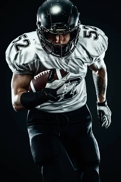 Американский футболист в шлеме в одиночестве бегает в действии на черном фоне. Спорт и мотивация обои . — стоковое фото