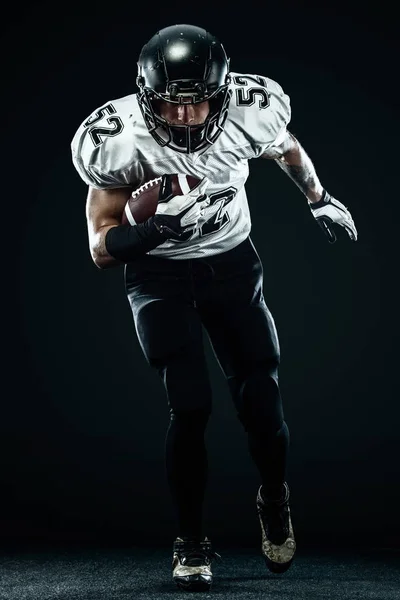 American Football Sportler mit Helm isoliert Lauf in Aktion auf schwarzem Hintergrund. Sport und Motivation Tapete. — Stockfoto