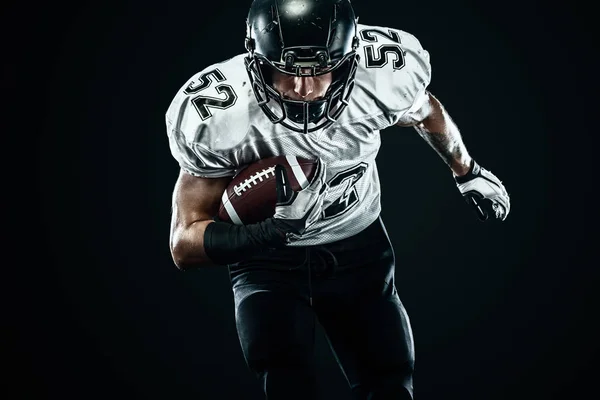 American Football Sportler mit Helm isoliert Lauf in Aktion auf schwarzem Hintergrund. Sport und Motivation Tapete. — Stockfoto