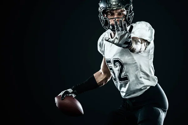 Американский футболист в шлеме изолирован на черном фоне. Спорт и мотивация обои . — стоковое фото