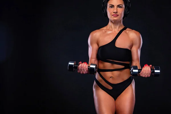 Ισχυρή μυϊκή bodybuilder αθλητική γυναίκα άντληση μυών με βαράκια σε μαύρο φόντο. Προπόνηση bodybuilding ιδέα. — Φωτογραφία Αρχείου