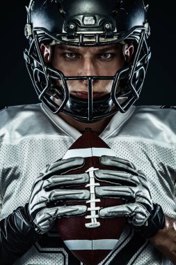 Kask lı Amerikalı futbolcu siyah arka planda hareket halinde. Spor ve motivasyon duvar kağıdı. Takım sporları,