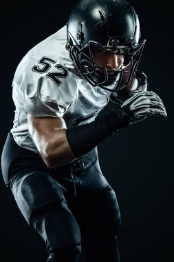 Kask lı Amerikalı futbolcu siyah arka planda hareket halinde. Spor ve motivasyon duvar kağıdı. Takım sporları,