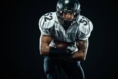 Kask lı Amerikalı futbolcu siyah arka planda hareket halinde. Spor ve motivasyon duvar kağıdı. Takım sporları,