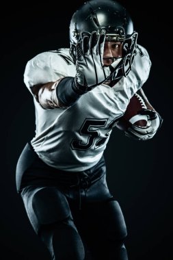 Kask lı Amerikalı futbolcu siyah arka planda hareket halinde. Spor ve motivasyon duvar kağıdı. Takım sporları,