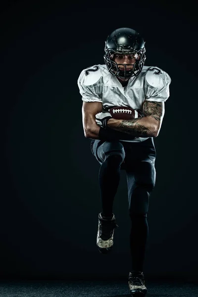 Jugador de fútbol americano deportista en casco aislado correr en acción sobre fondo negro. Fondo de pantalla de deporte y motivación. Deportes de equipo , —  Fotos de Stock