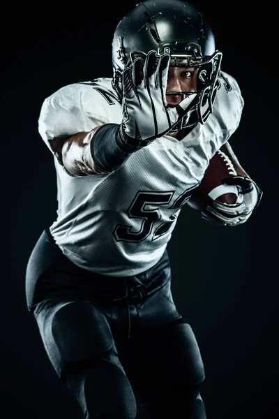 Jugador de fútbol americano deportista en casco aislado correr en acción sobre fondo negro. Fondo de pantalla de deporte y motivación. Deportes de equipo , — Foto de Stock