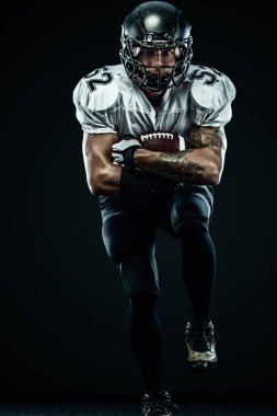 Kask lı Amerikalı futbolcu siyah arka planda hareket halinde. Spor ve motivasyon duvar kağıdı. Takım sporları,