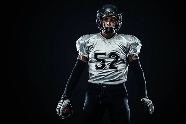 Giocatore sportivo di football americano in casco su sfondo nero. Sport e motivazione. Sport di squadra . — Foto Stock