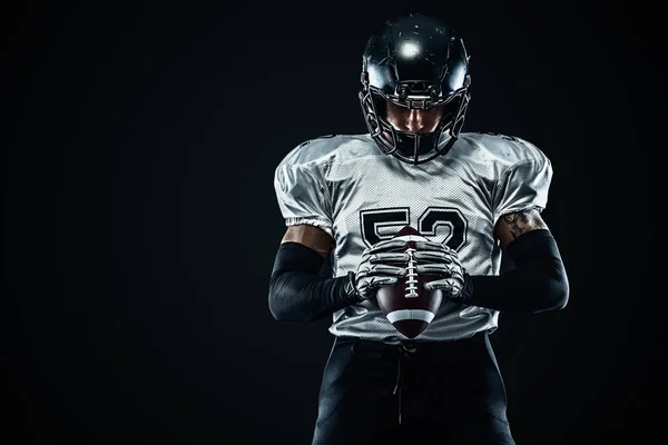 Giocatore sportivo di football americano in casco su sfondo nero. Sport e motivazione. Sport di squadra . — Foto Stock