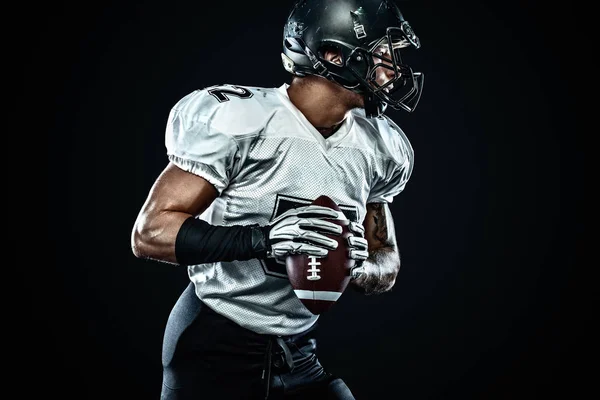 Giocatore sportivo di football americano in casco su sfondo nero. Sport e motivazione. Sport di squadra . — Foto Stock