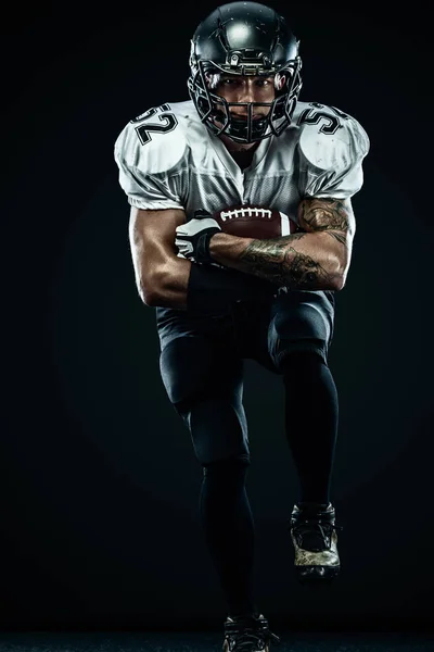 American Football Sportler mit Helm isoliert Lauf in Aktion auf schwarzem Hintergrund. Sport und Motivation Tapete. Mannschaftssport, — Stockfoto