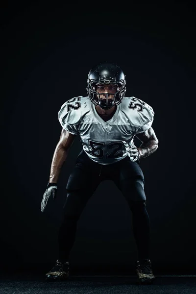 Giocatore sportivo di football americano in casco su sfondo nero. Sport e motivazione. Sport di squadra . — Foto Stock