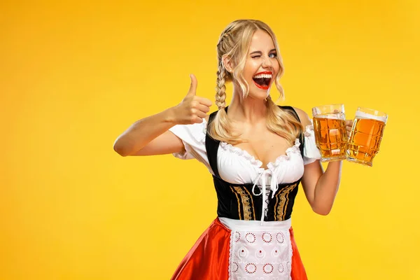 Wow emotie. Jonge sexy Oktoberfest meisje serveerster, het dragen van een traditionele Beierse of Duitse Dirndl, serveren grote bier mokken met drankje geïsoleerd op gele achtergrond. — Stockfoto