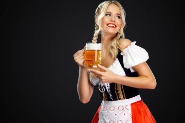 Gülümseyen genç seksi oktoberfest kız garson, geleneksel Bavyera veya Alman dirndl giyen, siyah arka plan izole içki ile iki büyük bira kupaları hizmet.