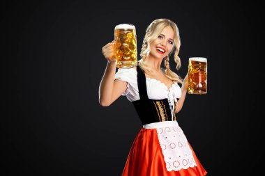 Mutlu seksi oktoberfest kız garson, geleneksel Bavyera veya Alman dirndl giyen, siyah arka plan izole içki ile iki büyük bira kupaları hizmet.