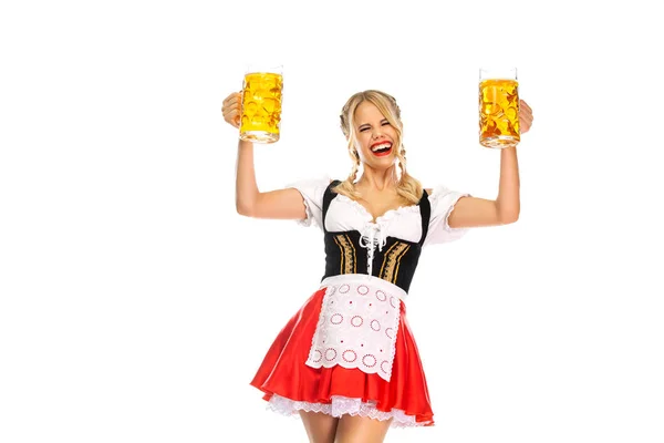 Junge sexy Oktoberfest-Kellnerin, die ein traditionelles bayerisches oder deutsches Dirndl trägt und zwei große Bierkrüge mit Getränken auf weißem Hintergrund serviert. — Stockfoto