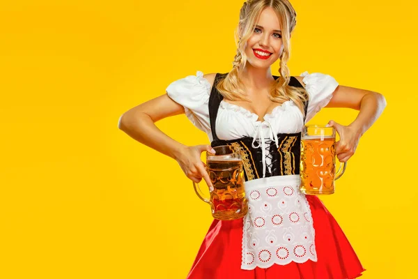 Vay canına duygu. Genç seksi Oktoberfest kız garson, geleneksel Bavyera veya Alman dirndl giyen, sarı arka plan izole içki ile büyük bira kupaları hizmet. — Stok fotoğraf