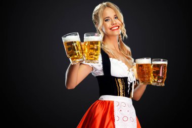 Genç seksi oktoberfest kız garson, geleneksel Bavyera veya Alman dirndl giyen, siyah arka plan izole içki ile iki büyük bira kupaları hizmet.