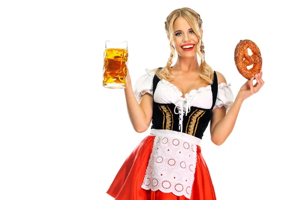 Lächelnde junge sexy Oktoberfestkellnerin, die ein traditionelles bayerisches oder deutsches Dirndl trägt, große Bierkrüge mit Getränken und Brezeln serviert, isoliert auf weißem Hintergrund. — Stockfoto