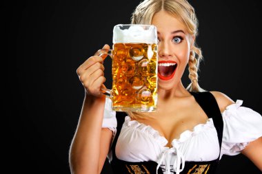 Gülümseyen genç seksi oktoberfest kız garson, geleneksel Bavyera veya Alman dirndl giyen, siyah arka plan izole içki ile büyük bira kupa hizmet.