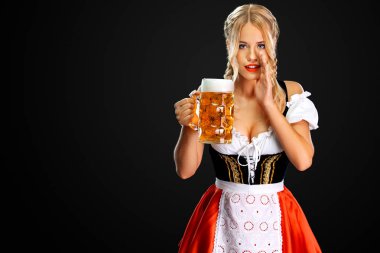 Seksi oktoberfest kız garson, geleneksel Bavyera veya Alman dirndl giyiyor, siyah arka plan izole içki ile büyük bira kupa hizmet vermektedir. Kadının bir sırrı var..
