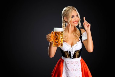 Gülümseyen genç seksi oktoberfest kız garson, geleneksel Bavyera veya Alman dirndl giyen, siyah arka plan izole içki ile büyük bira kupa hizmet.