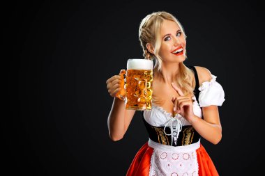 Gülümseyen genç seksi oktoberfest kız garson, geleneksel Bavyera veya Alman dirndl giyen, siyah arka plan izole içki ile büyük bira kupa hizmet.