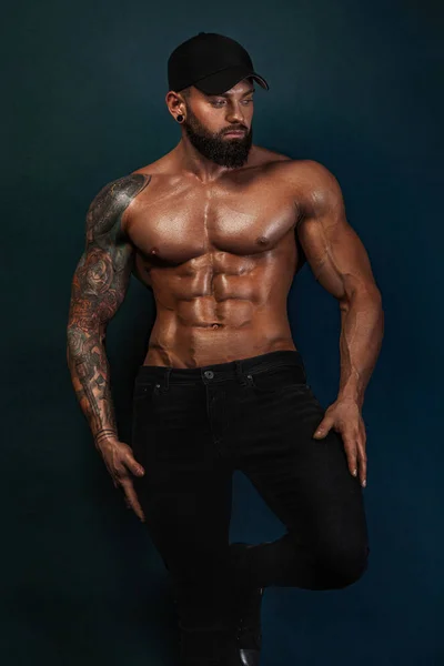 Güçlü ve zinde adam vücut geliştirmeci çıplak göğüslü siyah beyzbol şapkası. Sportif kaslı adam atlet. Spor ve fitness konsepti. Erkek modası.