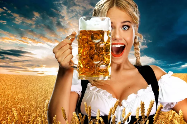Mosolygós fiatal szexi Oktoberfest lány pincérnő, fárasztó egy hagyományos bajor vagy német Dirndl, kiszolgáló nagy sörösbögre itallal kültéri. — Stock Fotó