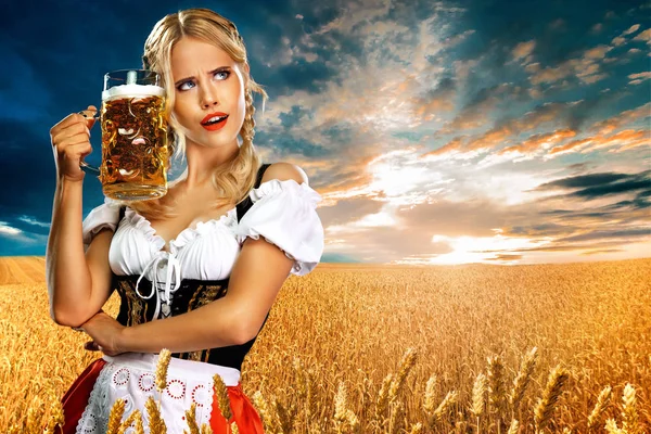 Sexy Oktoberfest-Kellnerin, in einem traditionellen bayerischen oder deutschen Dirndl, serviert großen Bierkrug mit Drink im Freien. — Stockfoto