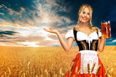 Genç seksi Oktoberfest kız garson, geleneksel Bavyera veya Alman dirndl giyen, açık içki ile büyük bira kupa tutarak. Sola bakmayı gösteren kadın.
