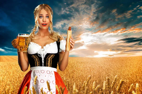 Garçonete sexy jovem Oktoberfest menina, vestindo um dirndl tradicional bávaro ou alemão, servindo canecas de cerveja grande com bebida e cachorro quente francês ao ar livre . — Fotografia de Stock