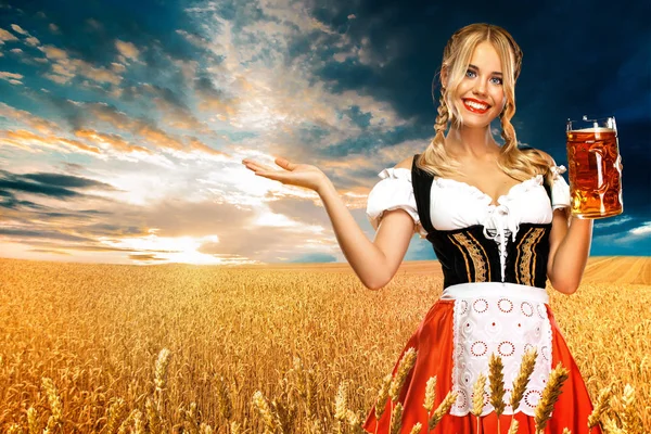 Jonge sexy Oktoberfest meisje serveerster, het dragen van een traditionele Beierse of Duitse Dirndl, het houden van grote Bierpul met drankje buiten. Vrouw wijzend naar links kijken. — Stockfoto