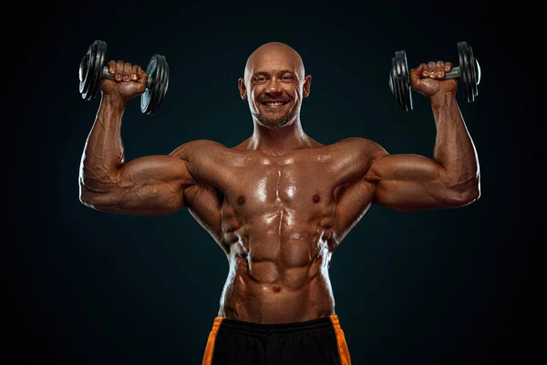 Bodybuilder uomo forte e in forma. Un tipo muscoloso e sportivo con i manubri. Sport e motivazione al fitness. Attività ricreative sportive individuali . — Foto Stock